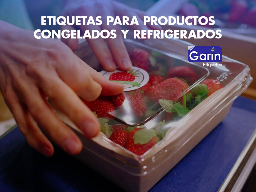 Fresas dentro de una caja de plástico y unas manos colocando etiquetas para productos refrigerados en ella